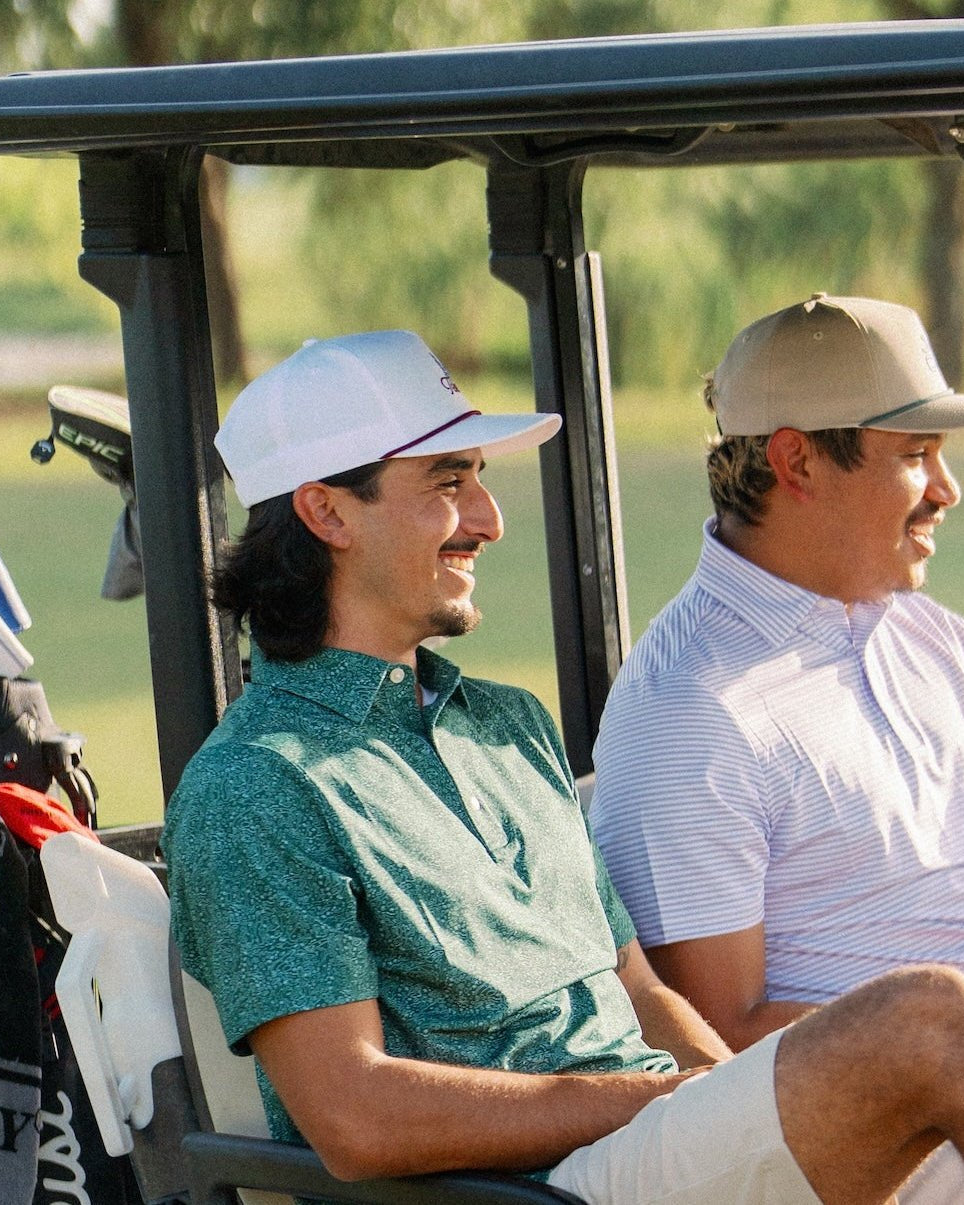 Two golfers in a cart at sunset, one wearing the Texas Bluebonnet Maroon Rope Hat