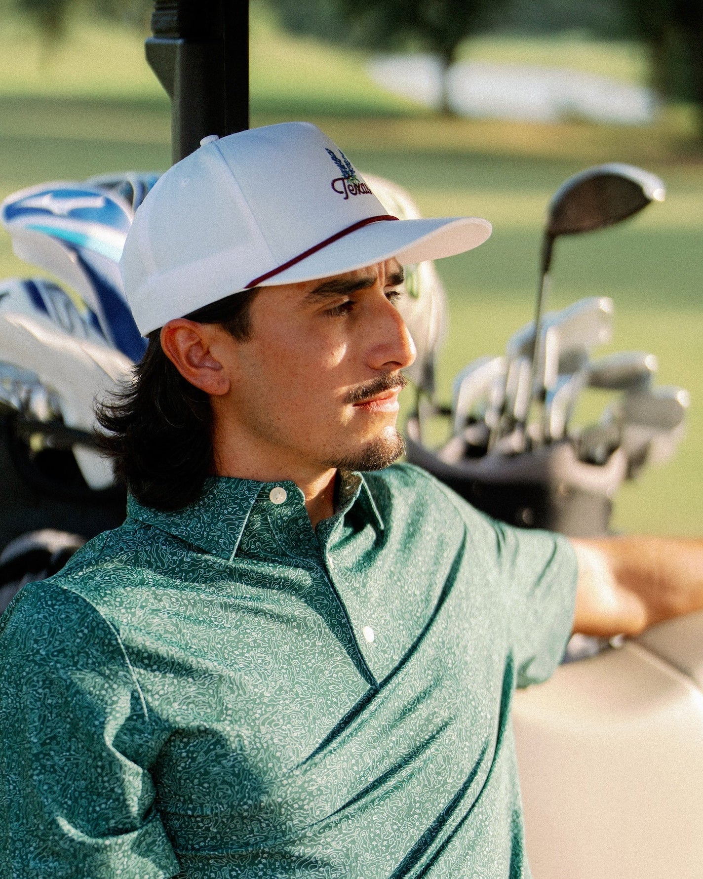 Side profile of a golfer in the Texas Bluebonnet Maroon Rope Hat beside his clubs