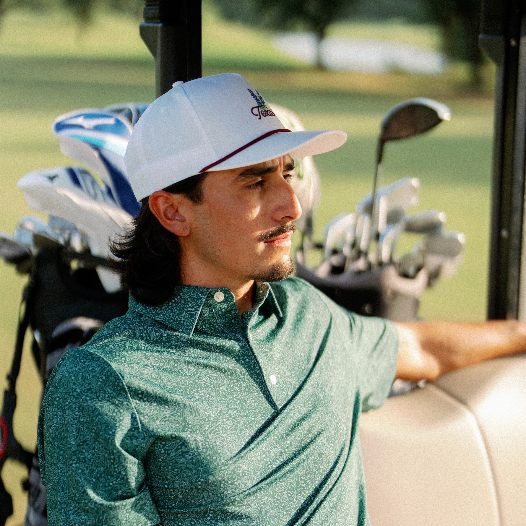 Side profile of a golfer in the Texas Bluebonnet Maroon Rope Hat beside his clubs
